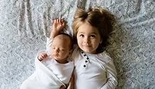 A toddler and a baby resting together